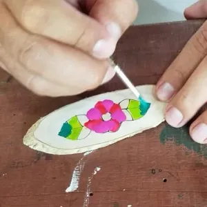 Manos pintando una pieza de artesanía en el taller