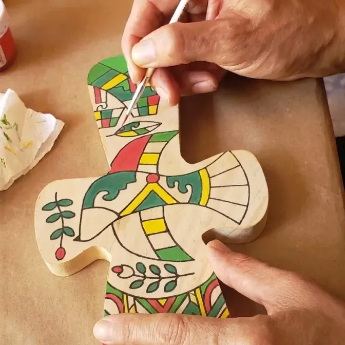 Manos pintando una pieza de madera en el taller