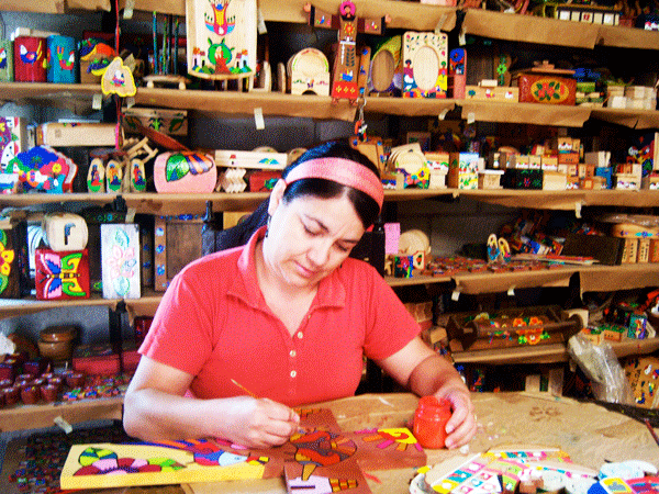 Estela Perlera painting a wooden craft